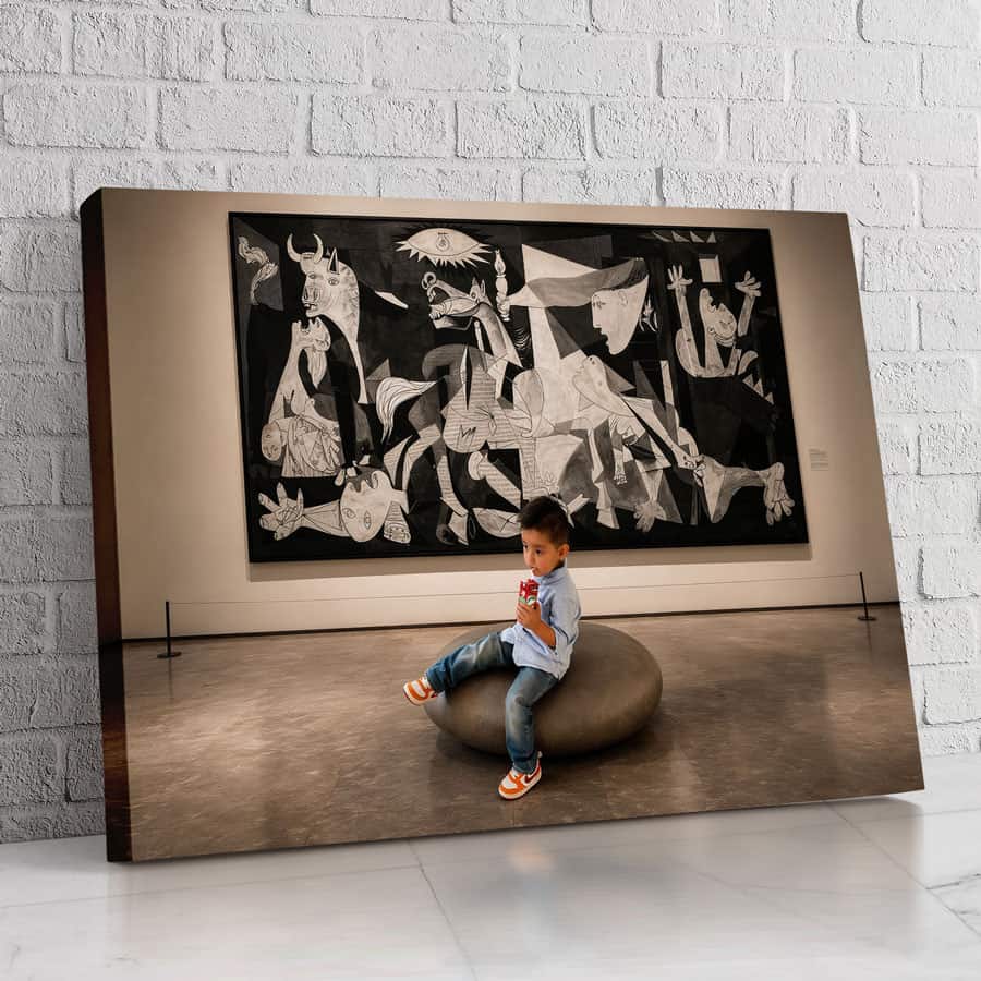 Niño sentado en escultura en galería de arte con obra abstracta en fondo.